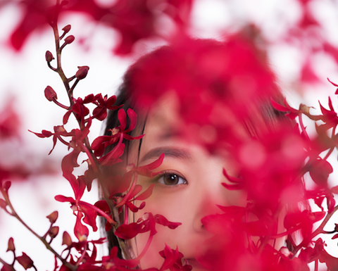 女性模特透過花卉之間的隙縫凝視前方,展現私密氛圍。